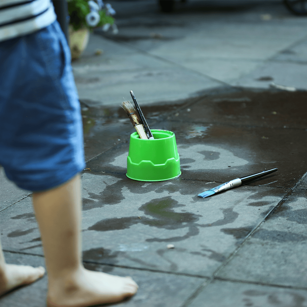 Child painting on pavement with water – creative backyard summer fun for kids